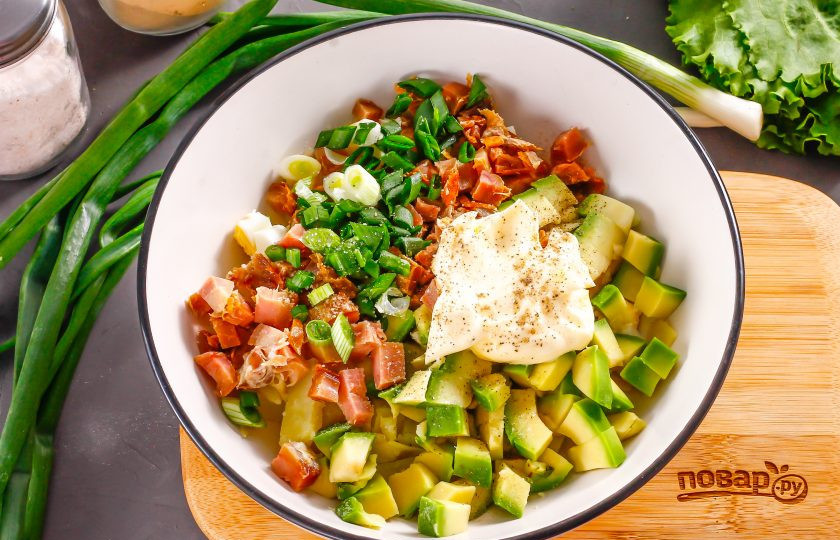 1. Этап. Салат с копченой курицей и авокадо: Промойте зеленый лук и измельчите, добавьте в емкость вместе с майонезом любой жирности, солью и молотым черным перцем. Аккуратно перемешайте все ингредиенты между собой.