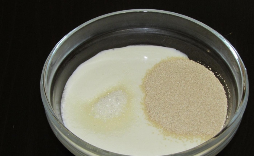 1. Этап. Оладьи на дрожжах и кефире: 1. Три столовые ложки кефира вливаю в миску, добавляю дрожжи и всыпаю щепотку сахара.