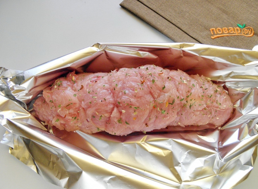 1. Этап. Новогодний рулет из индейки: Сверните мясо плотно в рулет. Свяжите кулинарной нитью. Заверните в фольгу и отправьте в духовку на 45 минут, температура — 180 градусов.