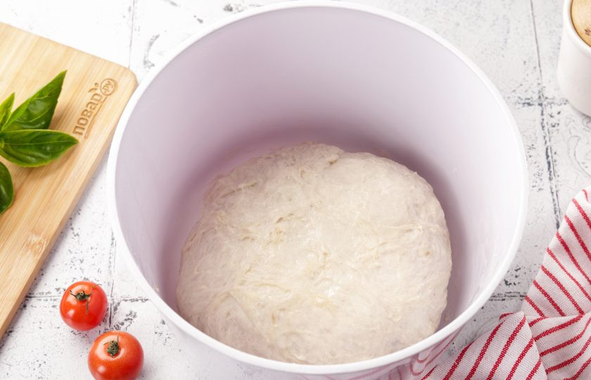 1. Этап. Пицца Нью-йорк: Перемешайте всё ещё раз ложкой, а затем продолжите замес руками. Тесто должно быть мягкое и чуть липкое. Смажьте руки растительным маслом, соберите тесто в шар, накройте миску полотенцем и оставьте в тёплом месте для подъёма, примерно на час-полтора.