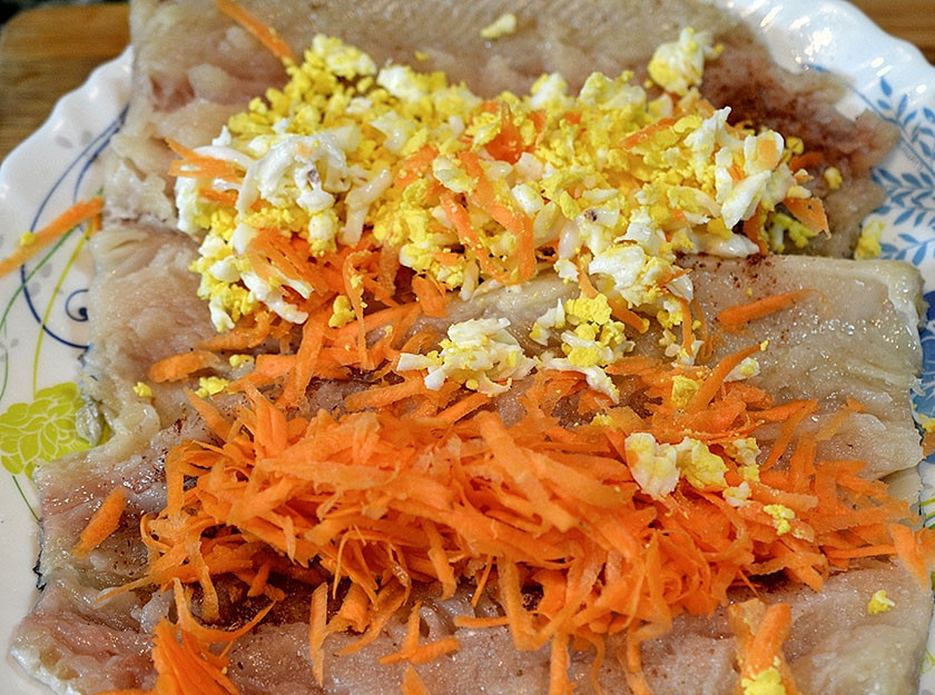 1. Этап. Рулет из рыбы с овощами: 2. У рыбы удалите хребет и головку, разрезав брюхо, и положите внахлест кожей вниз, посолите. Сверху выложите овощи.