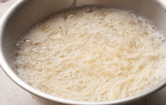 1. Этап. Подлива к картофельной запеканке: 1. Очистите картофель от кожуры, затем каждый натрите на крупной терке. В миску налейте воду и поместите в нее картофель, оставьте на 15-30 минут, чтобы избавиться от крахмала.