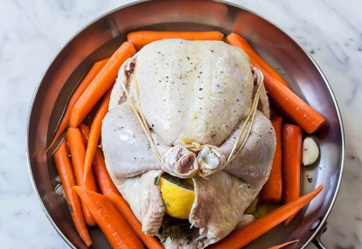 1. Этап. Запеченная курица с морковью: 5. Выложите куриную тушку на блюдо, очистите морковь и нарежьте ее тонкими ломтиками, затем выложите вокруг курицы. Влейте вокруг куриный бульон, а курицу смажьте растительным маслом.