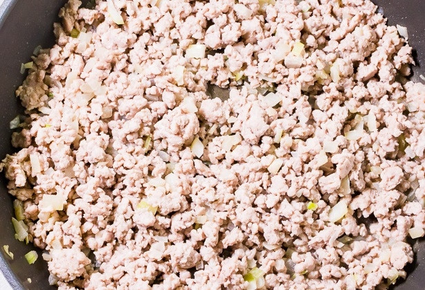 1. Этап. Свинина с изюмом: На сковороде разогрейте масло. Обжарьте в нём лук и чеснок до появления запаха. Затем добавьте фарш. Готовьте его до розоватого цвета, помешивая.