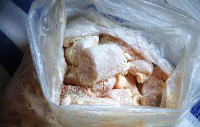 1. Этап. Куриные кусочки в яйце: Порежьте мясо кусочками, сложите в пакет. Добавьте смесь муки, соли и перца, хорошо встряхните.