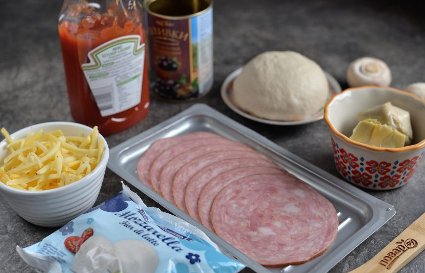 1. Этап. Пицца Каприччио: Разделите тесто на две одинаковые порции, подготовьте все ингредиенты для начинки для пиццы. Маслины нарежьте кружочками, натрите твердый сыр, артишоки откиньте на дуршлаг, чтобы убрать весь маринад.