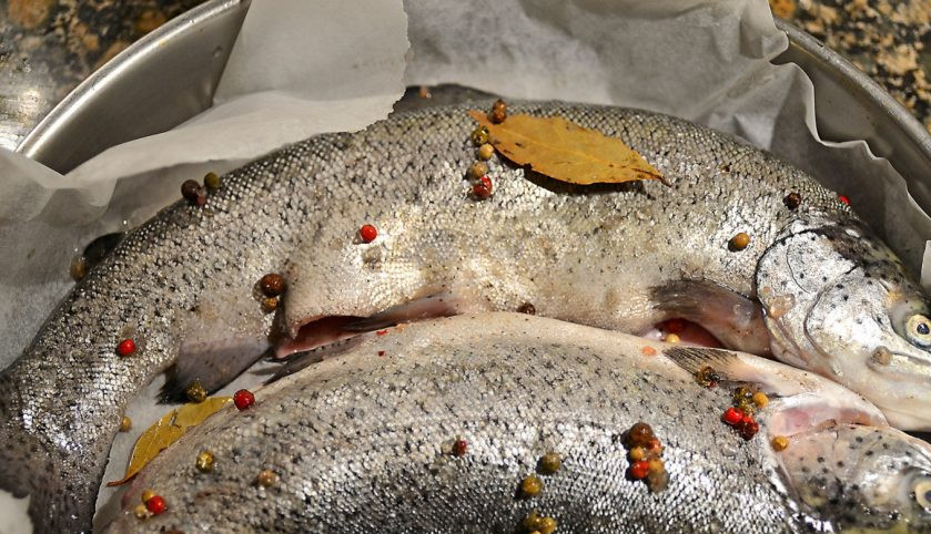 1. Этап. Речная рыба в духовке: В форму для запекания положите большой кусок пергаментной бумаги. Рыбу вымойте и обсушите, натрите солью и перцем, маслом и соком лимона, выложите в форму и добавьте лаврушку.