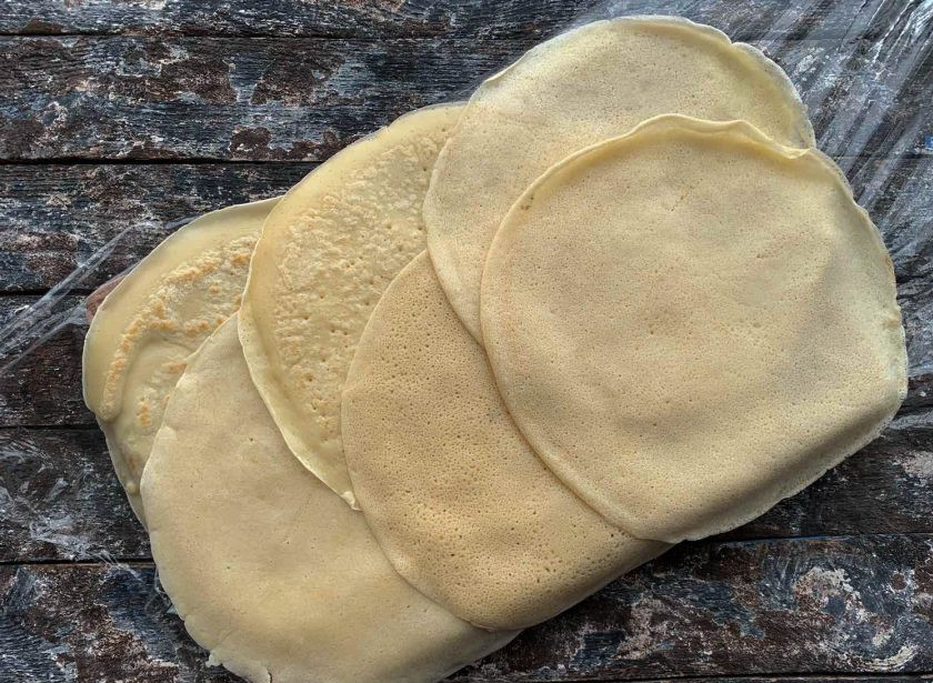 1. Этап. Блинный рулет с сыром: Разделочную доску накройте пищевой пленкой, и выложите блины в прямоугольник.