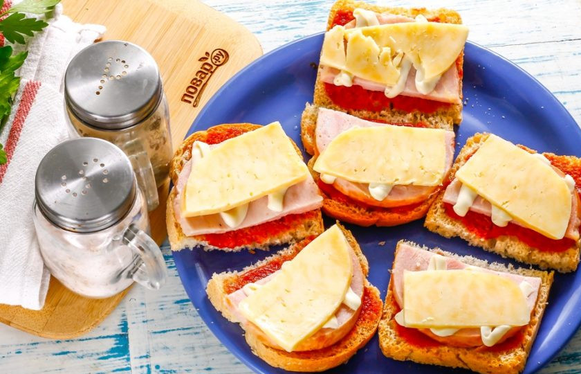 1. Этап. Бутерброды с ветчиной и сыром: Твердый сыр нарежьте ломтиками и выложите на майонез. По желанию его можно измельчить на терке и выложить - таким образом он больше обволочет бутерброды.