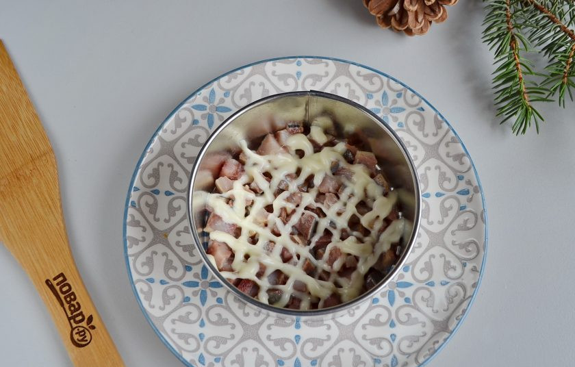 1. Этап. Салат-торт Селедка под шубой: Возьмите тарелочку, поставьте первое кольцо. Первый слой салата — селедка, майонезная сеточка.