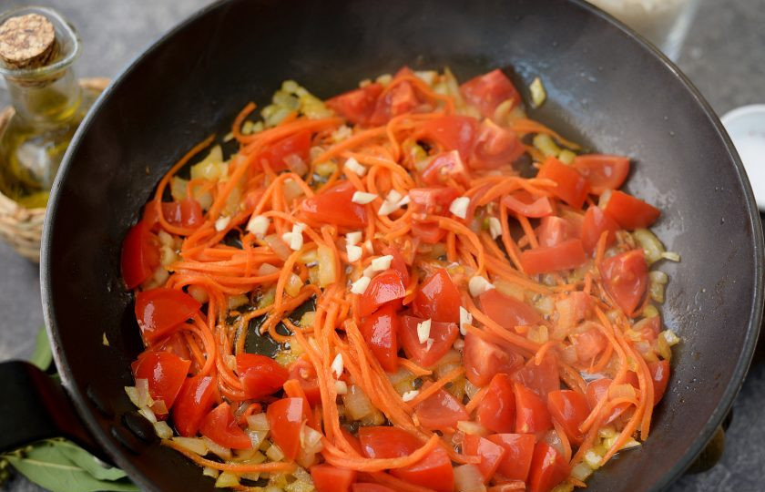 1. Этап. Плов с рапанами: Добавьте измельченные помидоры и нарубленный чеснок, тушите на умеренном огне еще минуты 3-4.