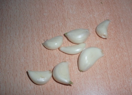 1. Этап. Огурцы Теща и зятек: В высушенные банки положите на дно 3 зубчика чеснока (в каждую). Укроп и хрен пропарьте в дуршлаге над кастрюлей и также положите в банки.