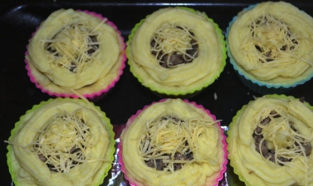 1. Этап. Картофельные гнезда: Сейчас пришло время сформировать гнёзда. Картофель выложите в бумажные формочки для кексов. Это очень удобно. Но также просто можно выложить картофель на противень, сделав в нём углубление для начинки. В гнёзда положите фарш, сверху присыпьте тёртым сыром.