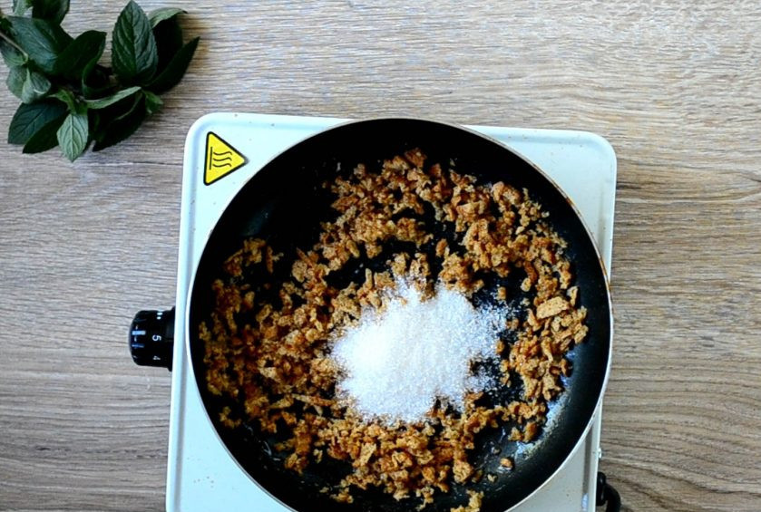 1. Этап. Яблочный крамбл с мороженым: На сковороде растопите половину сливочного масла, добавьте крошку из печенья и хорошо размешайте. Через минуту добавьте сахар и прогрейте еще в течение 1-2 минут, пока сахар не растает.