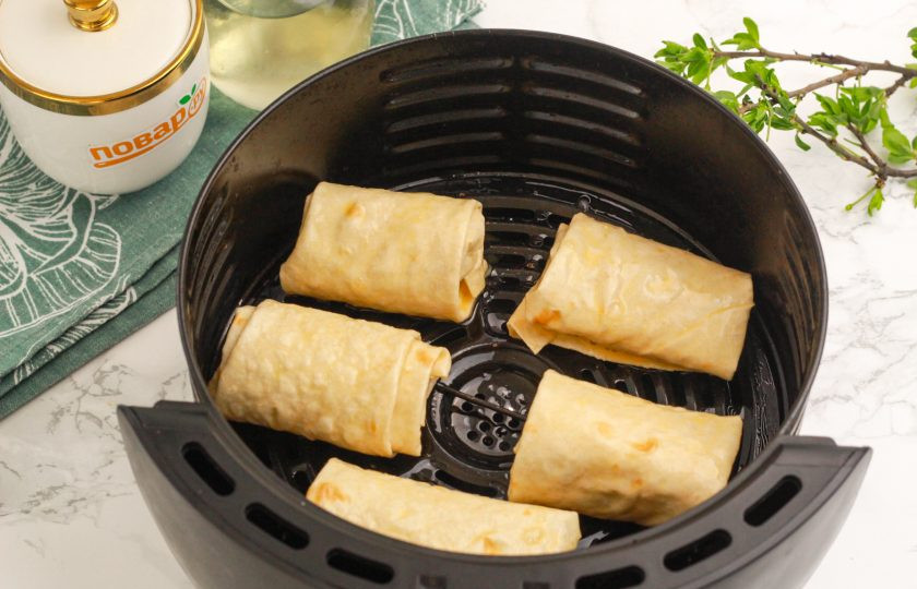 1. Этап. Лаваш с творогом в аэрогриле: Смажьте поддон аэрогриля растительным маслом и выложите на него заготовки на равном расстоянии друг от друга.