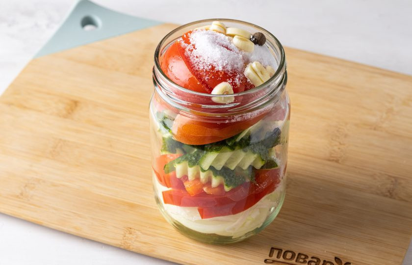 1. Этап. Салат на зиму с огурцами и помидорами: Влейте в банку уксус, добавьте сахар, соль, перец горошком и нарезанный пластинами чеснок.