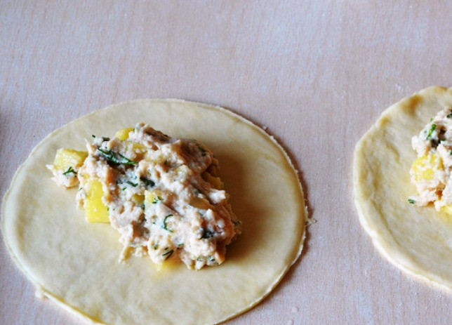 1. Этап. Расстегай с картошкой: Разделите тесто на части, раскатайте в пласт, в центр выложите начинку. Она состоит из порезанного кубиками картофеля и пропущенной через мясорубку вареной курятины с луком и зеленью.