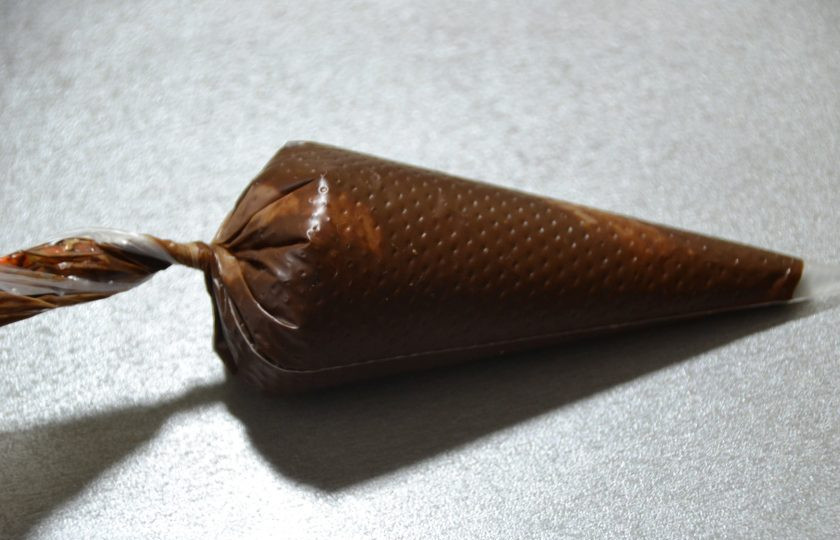 1. Этап. Итальянское печенье с миндалем: Переложите растопленный шоколад в маленький кондитерский мешок, срежьте кончик.