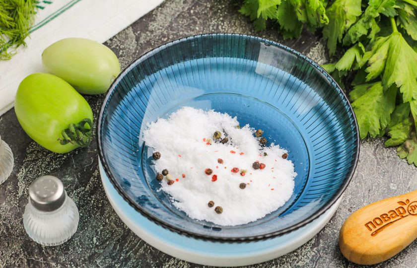 1. Этап. Как зеленые помидоры засолить на зиму в банках: Всыпьте соль и горошины перца в пиалу или другую емкость и залейте холодной отфильтрованной водой. Тщательно размешайте, чтобы соль растворилась.