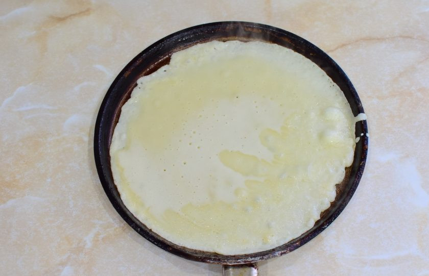 1. Этап. Блины на молоке с кипятком: Блинную сковороду разогрейте до горячего состояния и смажьте маслом. Налейте тесто и распределите его по всей поверхности сковороды тонким слоем.