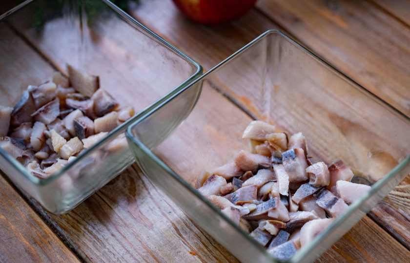 1. Этап. Салат Сельдь под одеялом: У меня два салатника, поэтому я все ингредиенты буду равномерно распределять между ними. Нарежьте филе сельди небольшими кубиками и выложите слоем на дно салатника.