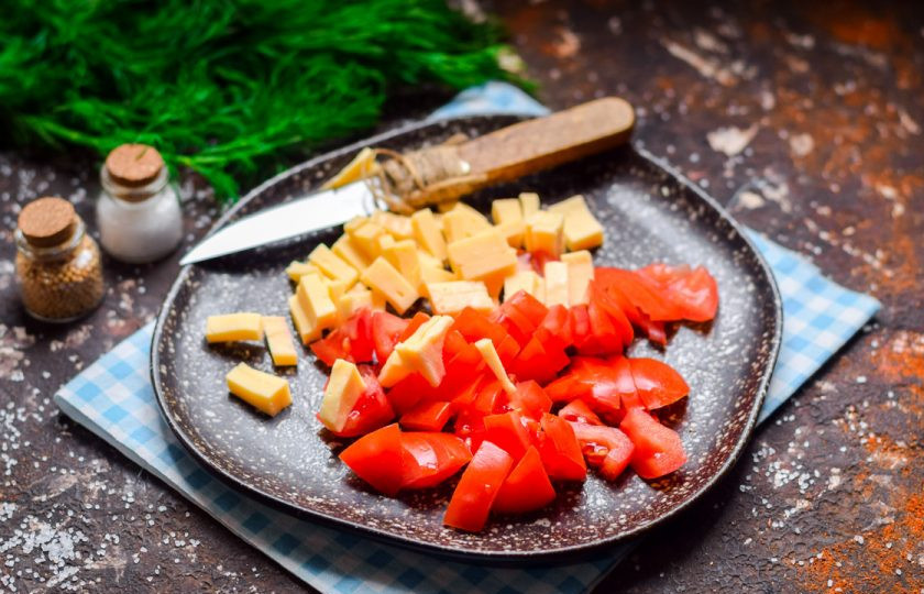 1. Этап. Салат из сыра, помидоров и крабовых палочек: Твердый сыр нарежьте кубиками небольшого размера. Добавьте сыр к помидорам.