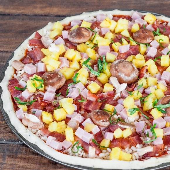 1. Этап. Пицца гавайская с ананасами: Смажьте основу пиццы соусом для пиццы, не жалея (можете взять томатную пасту или сальсу), потом посыпьте тертой моцареллой (или просто сыр порежьте кусочками) и равномерно нанесите на заготовку. Также равномерно распределите ветчину, бекон, грибы, ананасы и можете еще зелень добавить по вкусу.