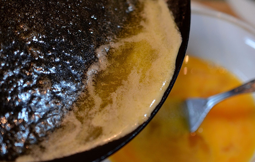 1. Этап. Омлетные роллы с зеленью и крабовыми палочками: 5. Растопленное масло горячим влейте в яйца, не прекращая помешивать вилкой.