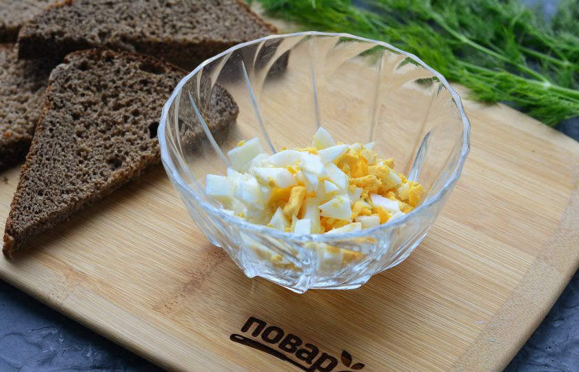 1. Этап. Бутерброды с молоками сельди: Сварите куриные яйца вкрутую, остудите, почистите и нарежьте кубиками. Всыпьте в удобную емкость.