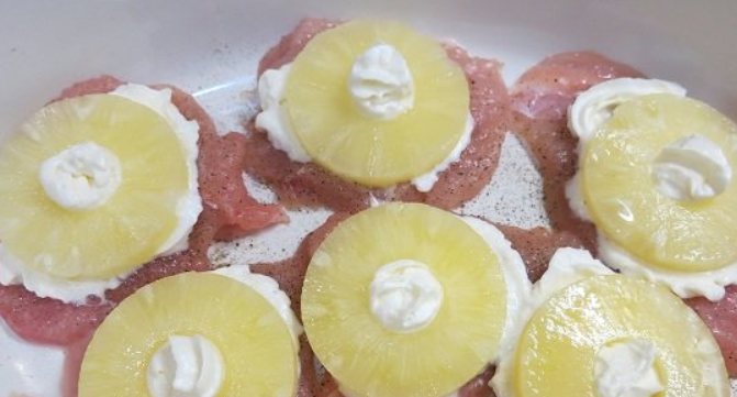 1. Этап. Куриная грудка с ананасами: Укладываем курицу в форму для запекания, застеленную пергаментом. На каждый кусок выдавливаем немного взбитых сливок и кладем кружочек ананаса.