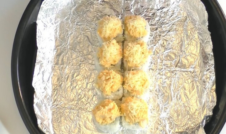 1. Этап. Роллы в духовке: На каждую часть ролла положите по 1 ч. л. начинки, которая в этом рецепте выступает и в качестве соуса, что облегчает приготовление роллов в духовке, но вкус блюда от этого только выигрывает. Сверху посыпьте тертым сыром.