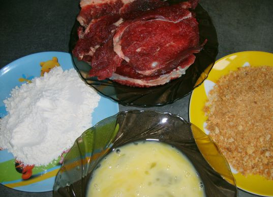 1. Этап. Говядина в сухарях: В плоскую тарелку насыпаем муку, в другую называем толченые сухари. В удобной (желательно тоже в плоской с углублением посуде) взбиваем яйцо. Сначала говядину обваливаем в муке, затем опускаем в яйцо, затем в сухари. Так делаем с каждым кусочком.