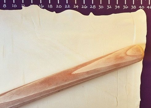 1. Этап. Штрудель яблочный из готового слоеного теста: Раскатаем слоеное тесто в прямоугольник и смажем мягким сливочным маслом. Затем поделим пласт теста на две части.