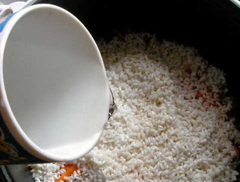 1. Этап. Свинина с рисом в мультиварке: Сверху выкладываем рис с которого предварительно слили воду. Заливаем все горячей водой. От количества воды зависит рассыпчатость вашего блюда. Если вы хотите получить более вязкую консистенцию, воды нужно налить приблизительно на 1 см выше риса.