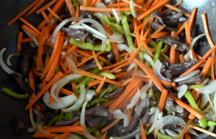 1. Этап. Маринованная говядина с овощами и зеленью: Добавьте репчатый лук, морковь и перец. Готовьте пару минут, постоянно помешивая.