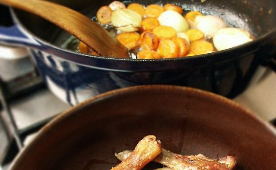 1. Этап. Гусь, тушенный с капустой: Кусочки гуся достаньте из казана, лишний жир слейте, оставьте приблизительно 100 мл. для обжарки овощей. Лук и морковь обжаривайте до румяной корочки.