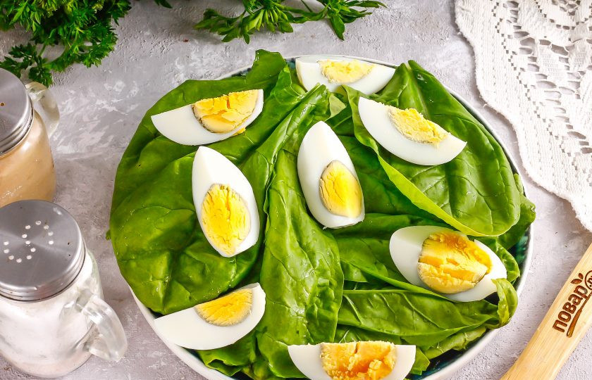 1. Этап. Низкокалорийный салат с тунцом: Очистите отварные куриные яйца от скорлупы, промойте в воде и нарежьте четвертинками. Выложите на шпинат. Можно использовать отварные перепелиные яйца, разрезая их пополам.