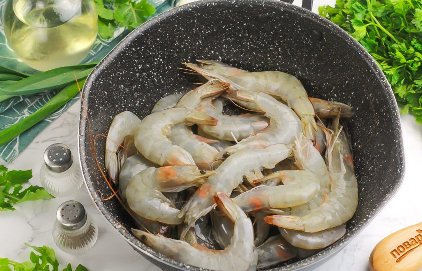 1. Этап. Жареные креветки с томатной пастой: Креветки промойте в воде, удалите усы, лапки (по желанию). Если они были замороженными, то обязательно разморозьте их перед началом приготовления и слейте лишнюю жидкость. Влейте в сковороду с высокими бортиками растительное масло, прогрейте его и выложите креветки.