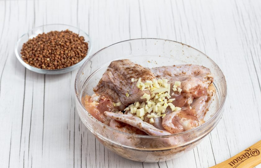 1. Этап. Куриные крылышки с гречкой: Масло смешайте с приправой, обмажьте крылышки. Добавьте рубленный чеснок и соль по вкусу. Снова перемешайте.