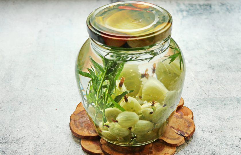 1. Этап. Компот Тархун из крыжовника на зиму: Залейте банку кипятком, прикройте крышкой и оставьте на 10 минут.