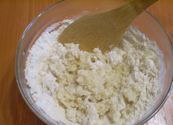 1. Этап. Заварное тесто для вкусных вареников: Влейте кипяток. Замешивайте сначала ложкой, а потом, когда немного остынет тесто, продолжайте вымешивать руками.