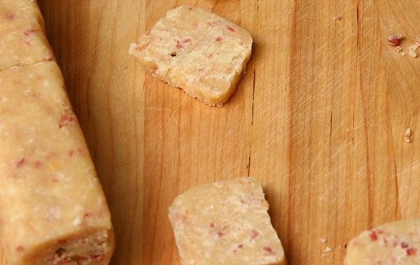 1. Этап. Коржики с беконом и Пармезаном: 2. Выложить тесто на большой лист пергаментной или вощеной бумаги. Скатать тесто в длинный прямоугольник диаметром 2,5 см. Завернуть в бумагу и заморозить в течение минимум 3 часов. Разогреть духовку до 200 градусов. Выстелить противень пергаментной бумагой или силиконовым ковриком. Нарезать тесто на ломтики толщиной около 6 мм