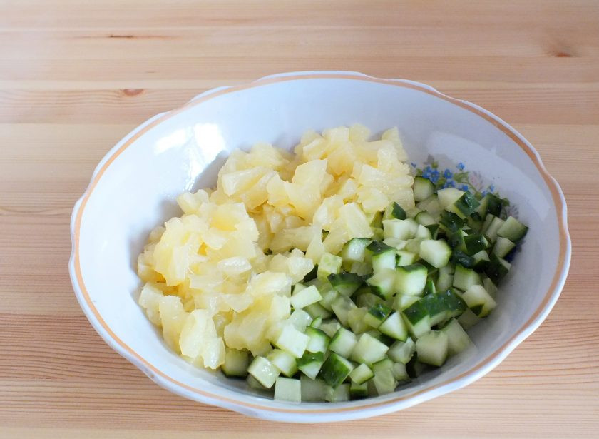 1. Этап. Салат из кальмаров, ананасов и огурцов: Возьмите глубокий салатник. Огурец и ананас нарежьте средним кубиком. Переложите в салатник.