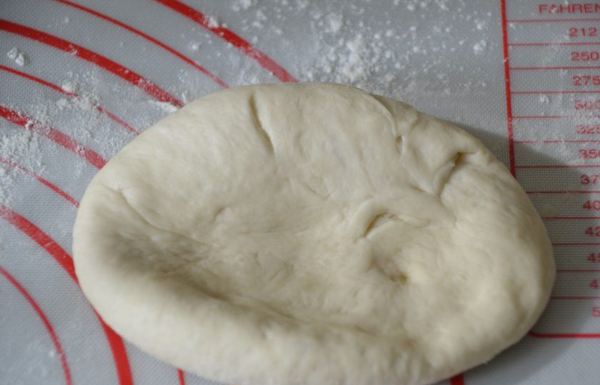 1. Этап. Булочки Римские чириолы: Сделайте из теста лепешку, основанием ладони сделайте пробивку в центр лепешки.