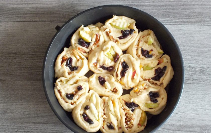 1. Этап. Дрожжевой пирог с яблоками и изюмом: Подготовьте круглую форму не менее 26 см. в диаметре. Застелите дно пекарской бумагой. Нарежьте рулет на 12-13 частей. Выложите по кругу формы, оставшиеся части в середину формы. Прикройте полотенцем и оставьте на 15 минут для подъема.