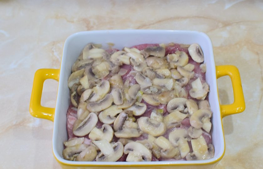1. Этап. Мясо по-орловски из свинины: Выложите обжаренные грибы на мясо.