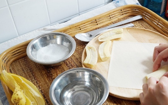 1. Этап. Спринг роллы с бананом: 2. Подготовьте немного сахара и мисочку с холодной водой. На лист бумаги выложите банан.