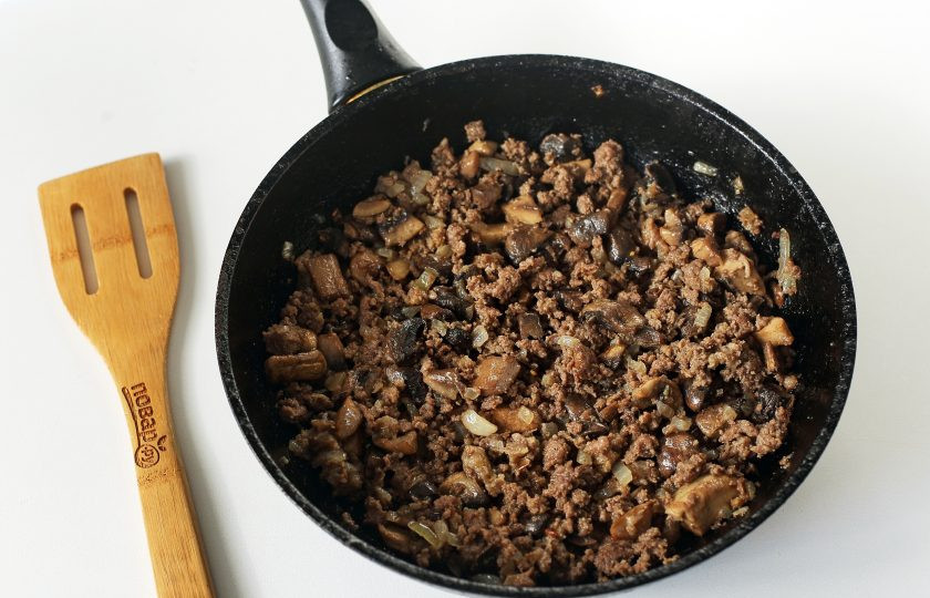 1. Этап. Слоеный пирог с мясом и грибами: Обжарьте до мягкости нарезанный кубиками лук. Добавьте нарезанные примерно такими же кубиками грибы и готовьте до испарения жидкости. Затем добавьте любой мясной фарш, соль по вкусу и любимые специи. Разбивая комочки фарша лопаткой готовьте все вместе около 2-3 минут. Если жидкости много, то готовьте до тех пор, пока вся вода не выпарится. Начинка готова.