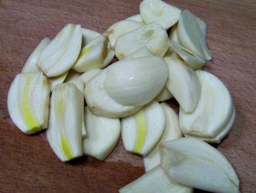 1. Этап. Капуста маринованная с чесноком и свеклой: 4. Очистите чеснок и нарежьте тонкими пластинками или небольшими кубиками. Часть выложите сверху капусты.