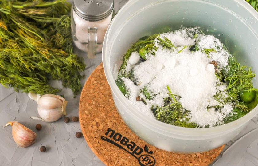 1. Этап. Соленые огурцы по ГОСТу: Всыпьте соль и горошины душистого перца. Сушеную гвоздику не добавляйте — ее добавляют только к маринованным огурцам.